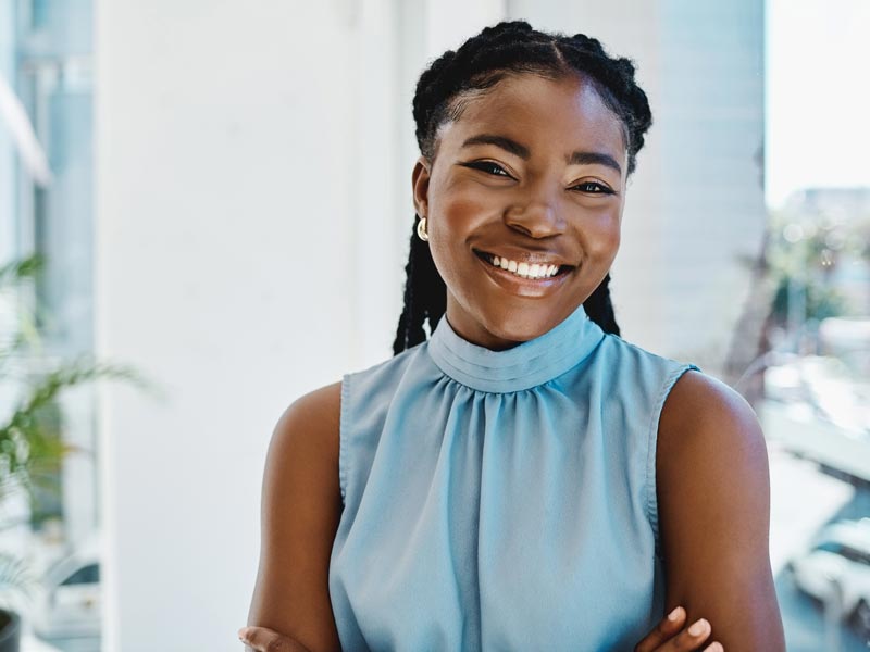 Confident young black businesswoman standing at a window in an office alone