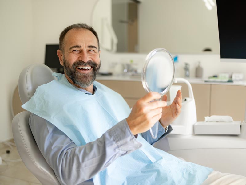 Happy male patient smiling at dentist office