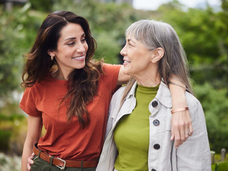 Smiling woman talking with her senior mom while walking outside