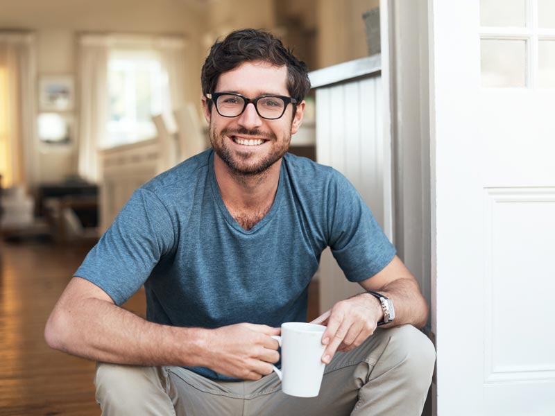 smiling young man holding cup of coffee